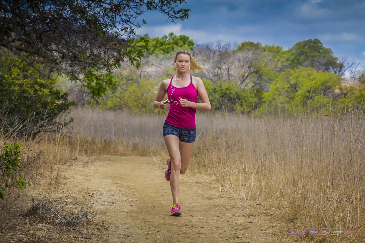 Model Kelly Pantaleoni running a trail in a fuchsia tank top, patterned shorts and pink Nike shoes Model Kelly Pantaleoni running a trail in a fuchsia tank top, patterned shorts and pink Nike shoes