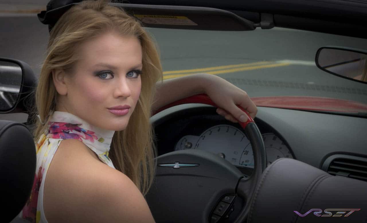 blonde female model blue eyes looking back at camera from car
