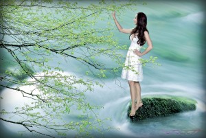 brunette female model touching tree branch river