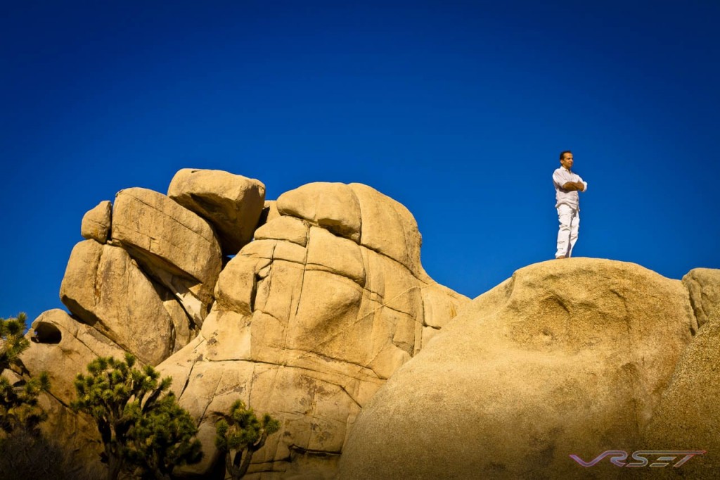 distance shot man standing arms crossed top huge rocks