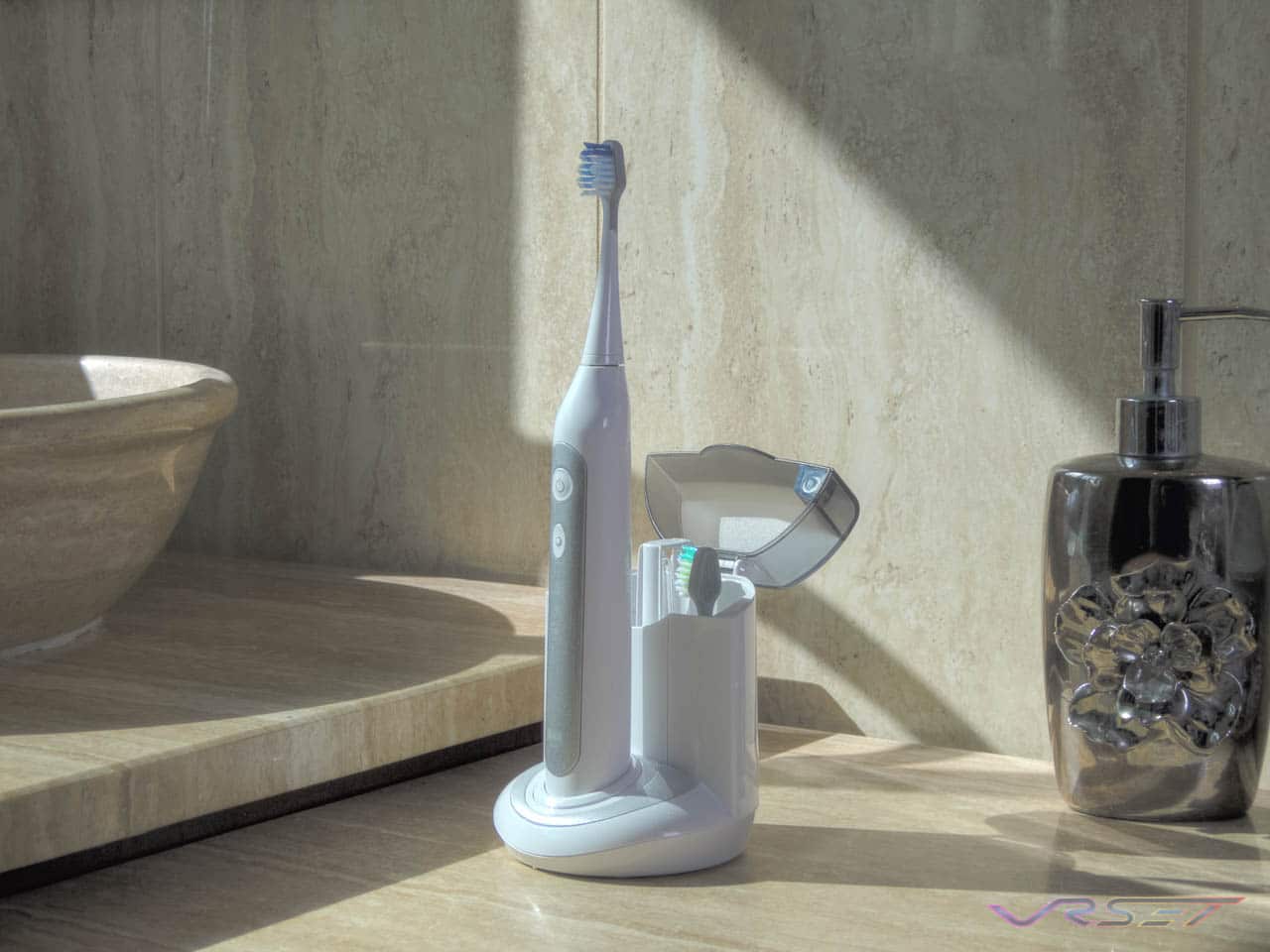 Rechargeable vibrating toothbrush beside its UV cleaning unit on a studio surface