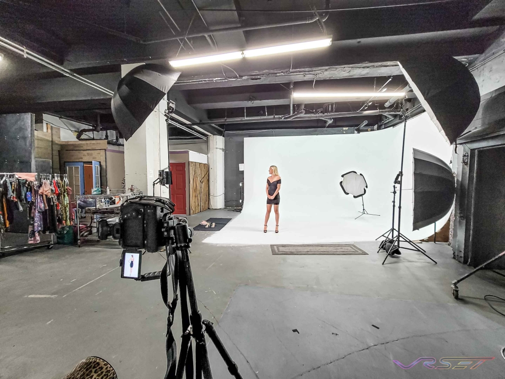 Rack of clothing and studio lighting plus professional camera getting setup at a clothing photography studio in Los Angeles