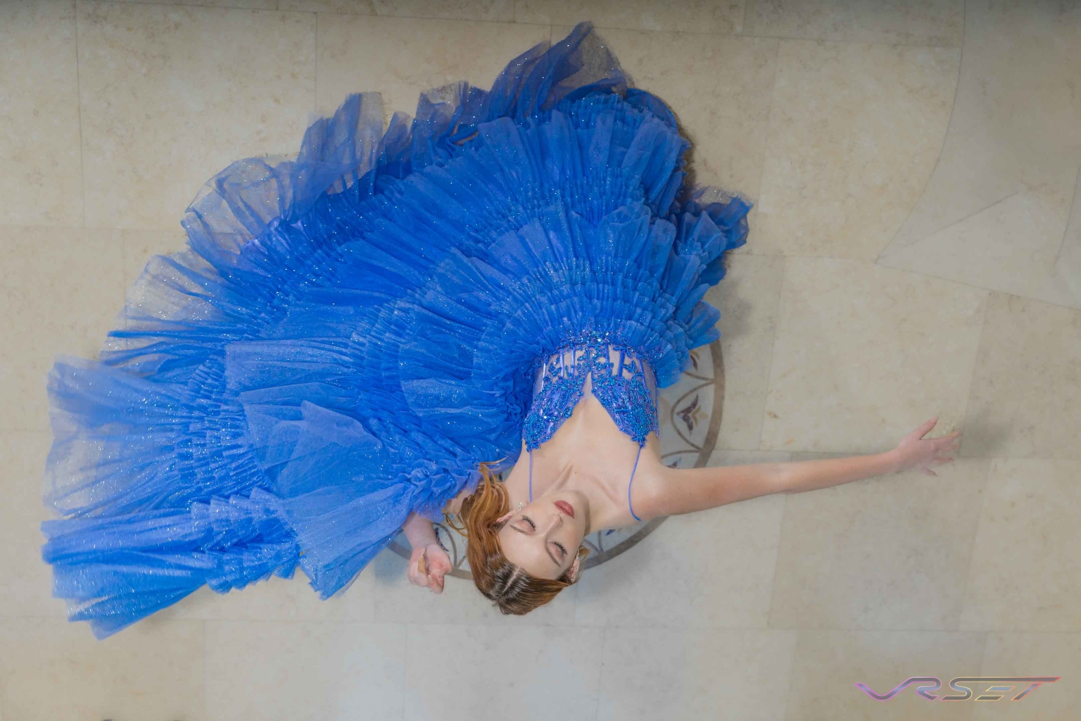 Overhead view of a model in a blue chiffon gown spread across the floor Overhead view of a model in a blue chiffon gown spread across the floor