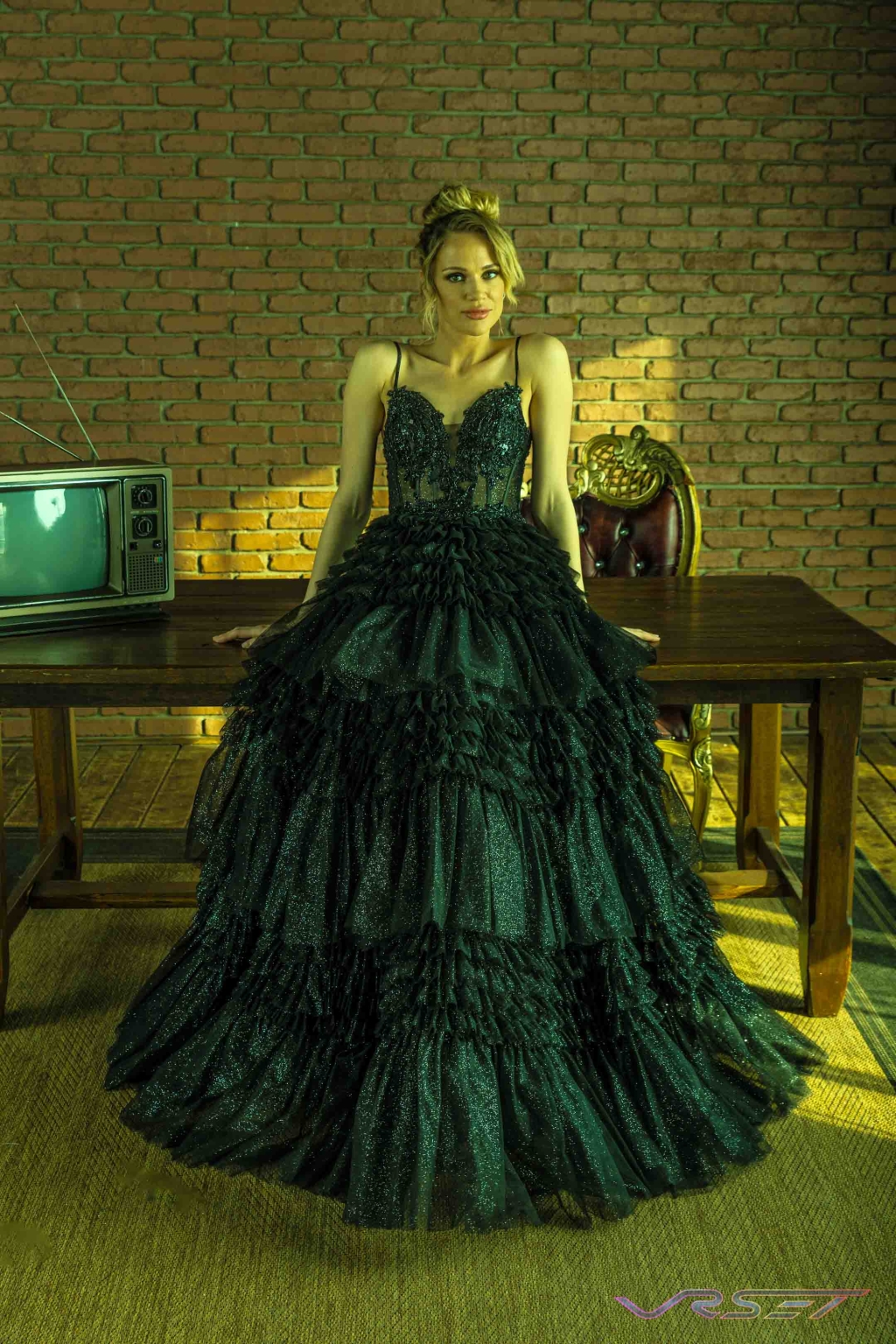 Model in a crystal-embroidered black gown against a dark, overcast editorial background