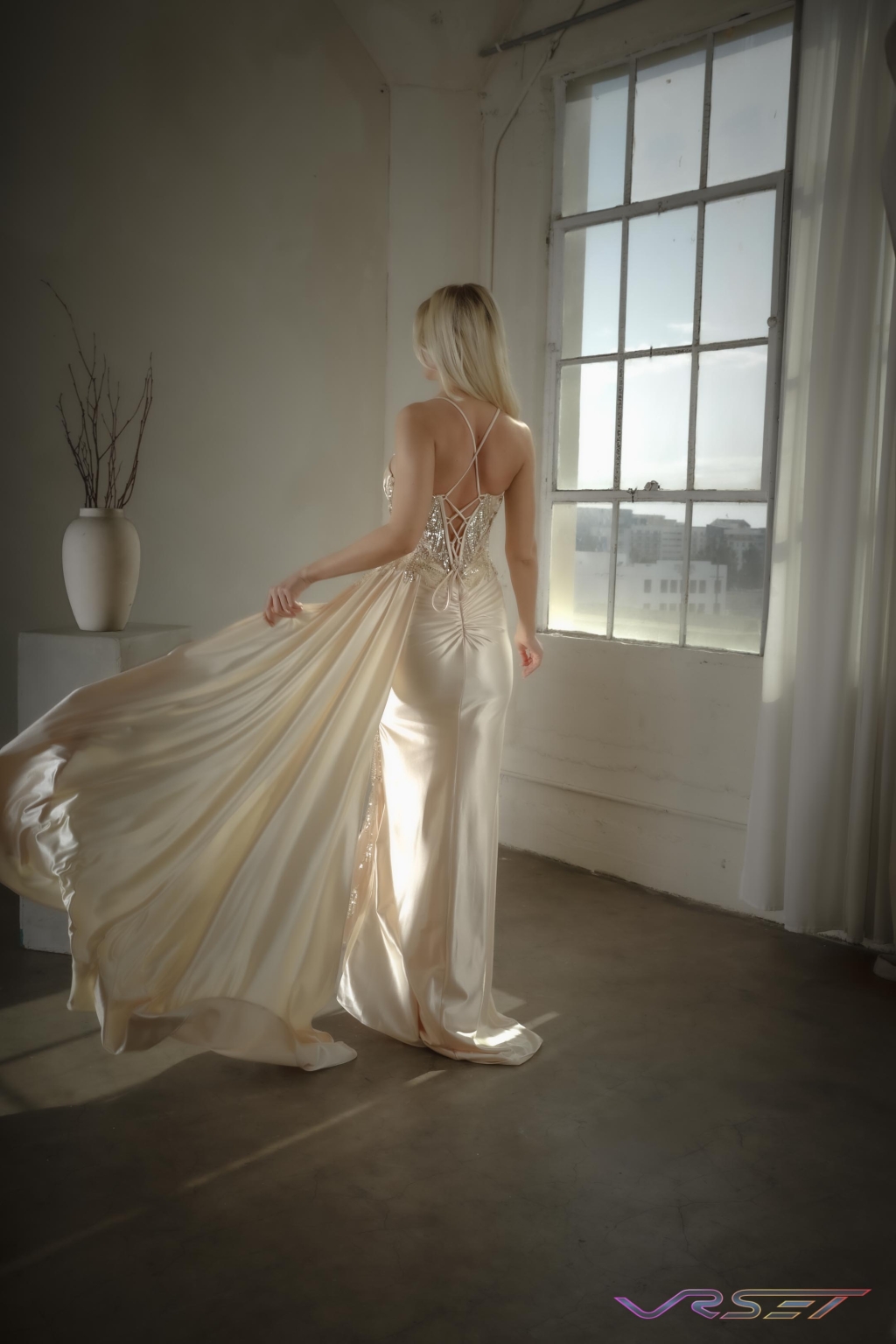 Model in a cream satin gown with crystal studding, lit against a studio background Model in a cream satin gown with crystal studding, lit against a studio background