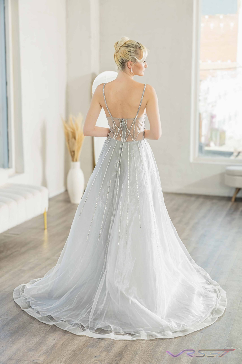 Model in a silver gown covered with crystal studs, lit against a plain studio backdrop Model in a silver gown covered with crystal studs, lit against a plain studio backdrop