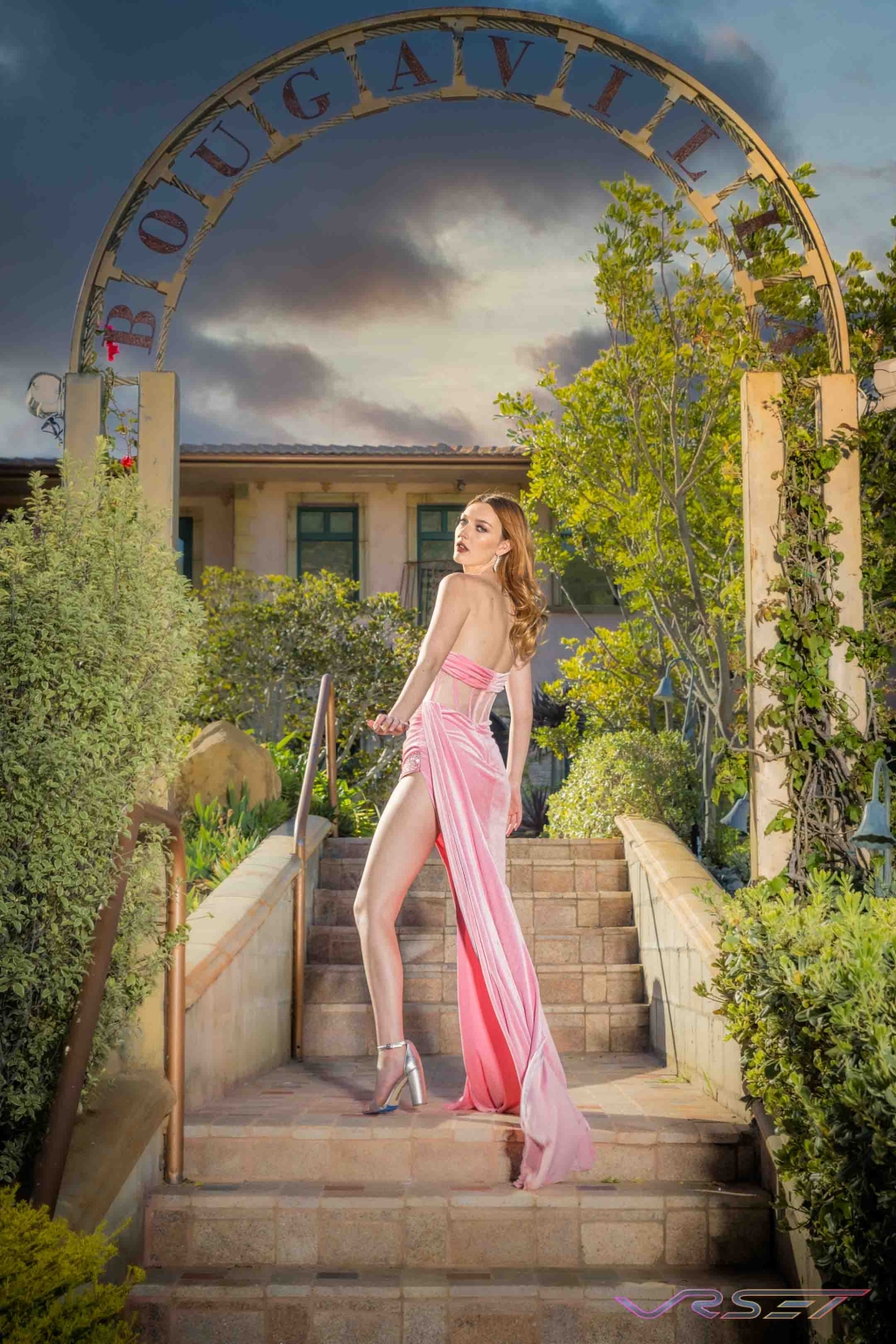 Model in a pink gown with a high slit, shot in a relaxed editorial setting Model in a pink gown with a high slit, shot in a relaxed editorial setting