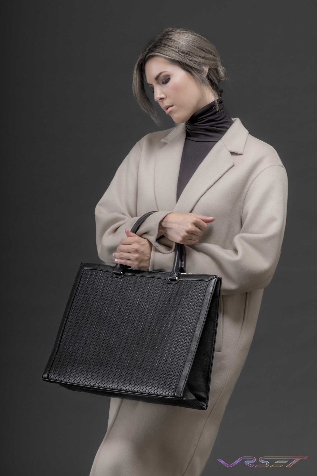 Structured black leather box tote standing upright with squared handles and base stitching visible